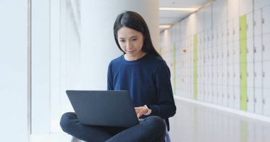 Üniversite kampüsü içinde dizüstü bilgisayar üzerinde çalışan kadın 