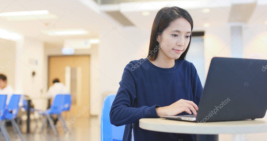 Woman working on laptop computer inside university campus 