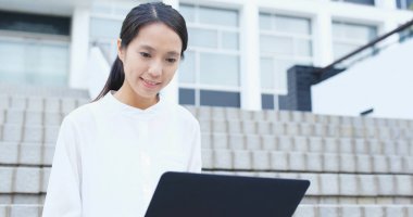 Dizüstü bilgisayar kullanan genç bir iş kadını. 