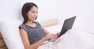 Yatakta onun köpeği ile dizüstü bilgisayar üzerinde çalışan kadın