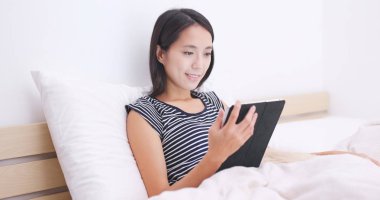 Tablete izliyor ve köpeğiyle yatakta yatarken kadın 