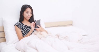 Evde yatakta cep telefonu kullanan kadın 