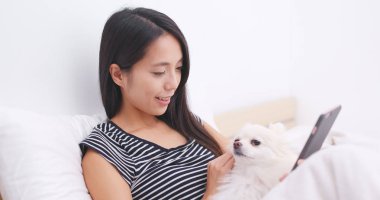 Yatakta onun köpeği ile cep telefonu kullanan kadın 