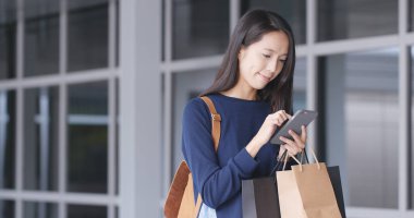Cep telefonu ve alışveriş torbaları kullanan kadın
