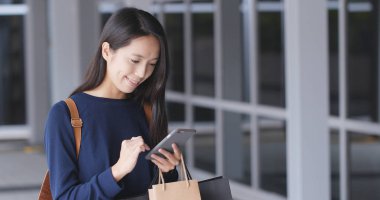 Cep telefonu ve alışveriş torbaları kullanan kadın 