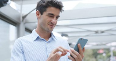 Beyaz işadamı cep telefonuyla şehirde 