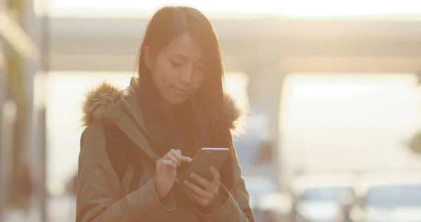 夕日の下で都市のスマート フォンを使用しての女性 — ストック写真