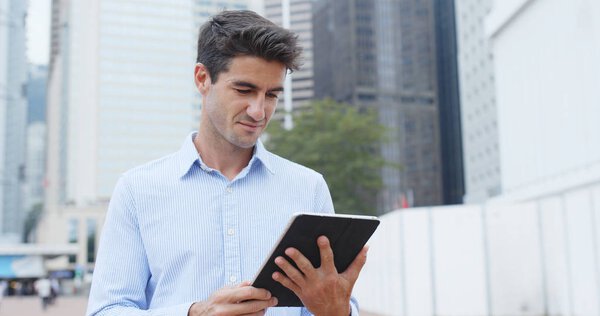Businessman holding tablet computer in city 