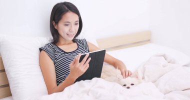 Yatakta onun köpeği ile tablet bilgisayar kullanan kadın 
