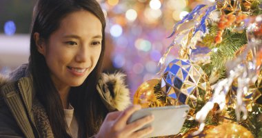 Kadın alarak resmi için cep telefonu ile Noel ağacı süsle 