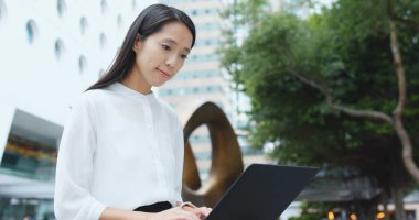 Şehirde dizüstü bilgisayar üzerinde çalışan kadın 