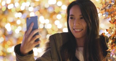 Kadın alarak resmi cellphone ile Noel ağacı süsle gece için 