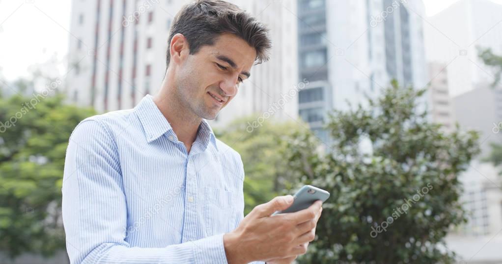 Caucasian businessman look at mobile phone in city 