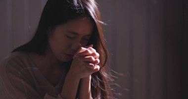 Christian woman praying in the dark 