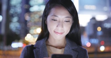 Asyalı kadın cep telefonu şehirde geceleri kullanarak. 