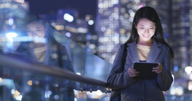 Kadın bir tablet bilgisayar geceleri kullanır. 