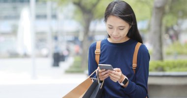 Smartphone kullanarak ve alışveriş sonra kağıt torba tutarak Asyalı kadın 