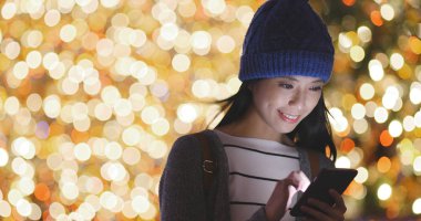 Bokeh arka plan üzerinde akıllı telefon kullanan kadın 