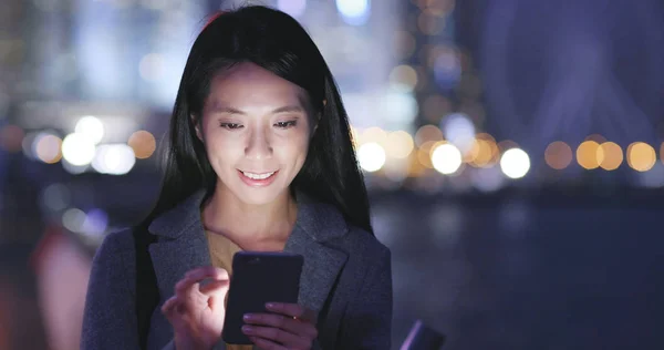 Woman look at mobile phone in city at night
