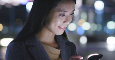 Kadın geceleri şehir içinde hareket eden telefon bakmak 