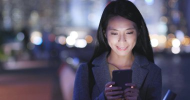 Genç kadın cep telefonu şehirde geceleri kullanarak. 