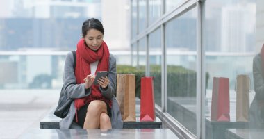 Cep telefonu ile onun kağıt çanta kullanan kadın 