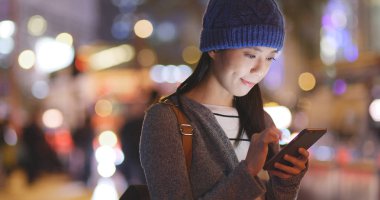 Kadın geceleri şehir içinde hareket eden telefon bakmak 