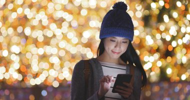 Bokeh arka plan üzerinde cep telefonu kullanan kadın 