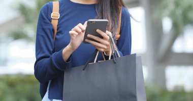 Cep telefonu ve çanta alışveriş tutar kullanan kadın