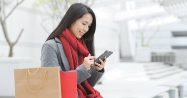 Kağıt torba tutarak ve cep telefonuyla şehirde alışveriş kadın 