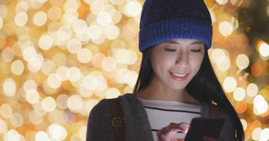 Bokeh arka plan üzerinde akıllı telefon kullanan kadın 