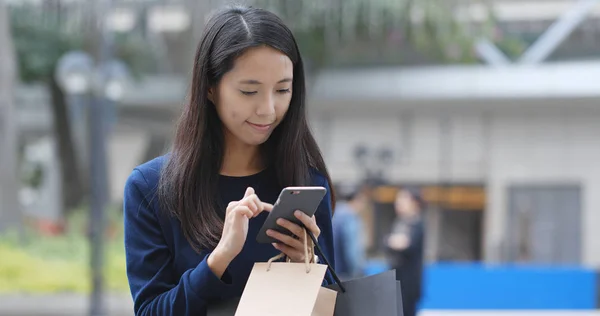 Frau Schaut Aufs Handy Und Hält Einkaufstüten Der Hand — Stockfoto