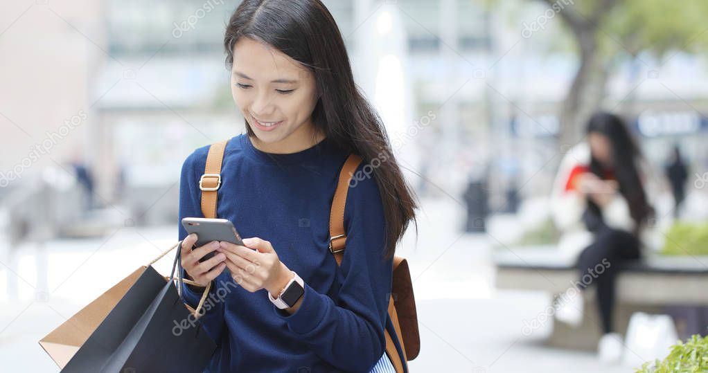 Woman using mobile phone and holding shopping bags 