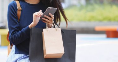 Cep telefonu ve Beklemeler kağıt torba kullanan kadın 