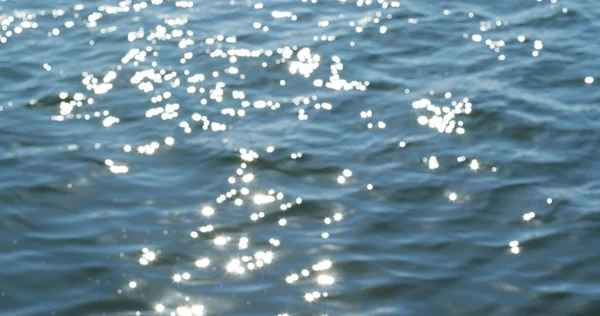 Defocused shot of a wavy water surface with a beautiful bokeh of sun glares