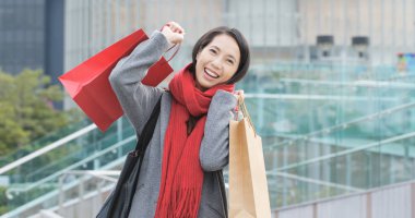 Cep telefonu kullaranarak ve alışveriş torbaları tutan kadın 