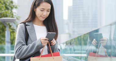 Alışveriş torbaları yanında koyarak ile cep telefonu kullanan kadın 