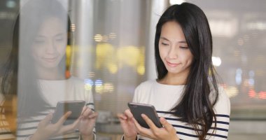 Şehir geceleri pencere yansıması ile cep telefonu kullanan kadın 