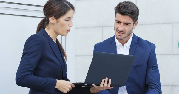 Business assistant showing the proposal on laptop computer to his boss outside office