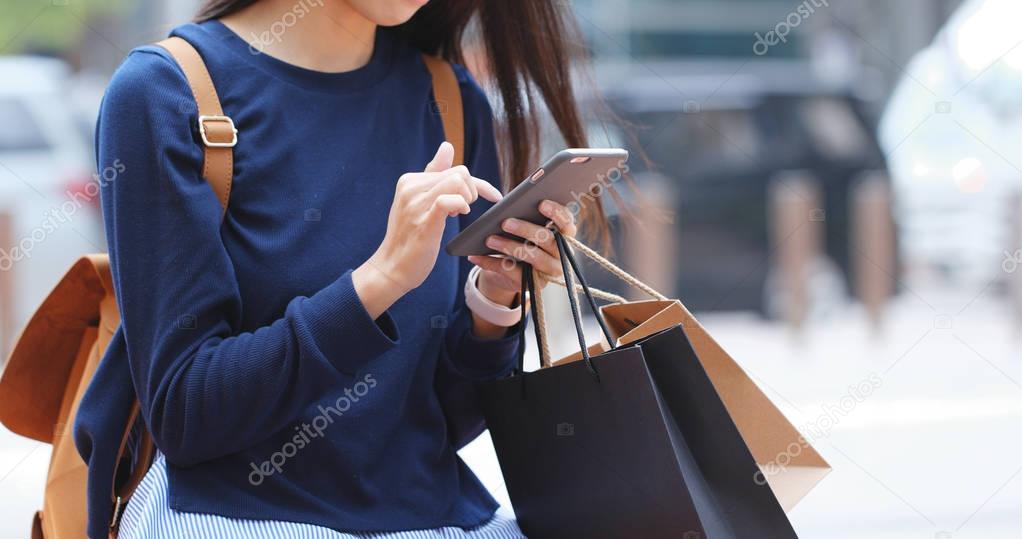 Woman look at mobile phone and holding shopping bags 