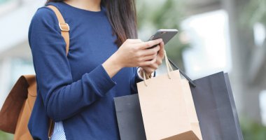 Cep telefonu ile kağıt çanta tutan kadın 