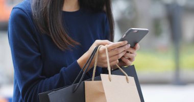 Kağıt torba ile akıllı telefon kullanan kadın 