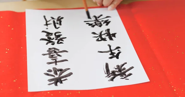 Writing Chinese calligraphy on write paper with phrase meaning may you have a prosperous New Year