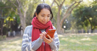 Parkta akıllı telefon kullanan kadın. 