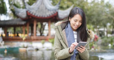 Asyalı kadın, cep telefonuyla Çin Çince Bahçe, kış ceket giyen kadın köşk. 