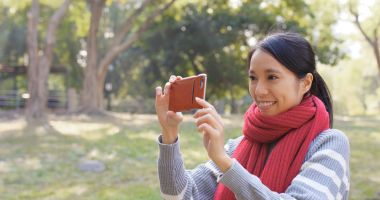 Alarak fotoğraf Park için cep telefonu kullanan kadın 