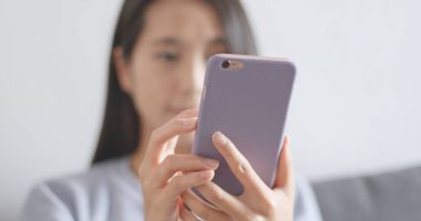 Evde cep telefonu kullanan bir kadın 