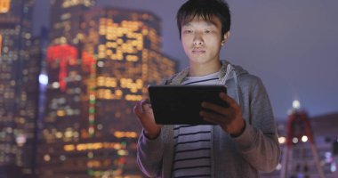 Geceleri tablet bilgisayar kullanan Asyalı adam 