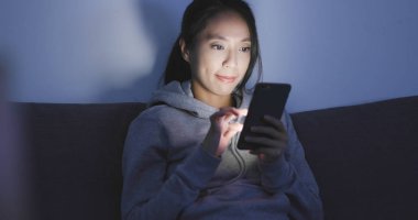 Geceleri cep telefonu kullanan bir kadın. 