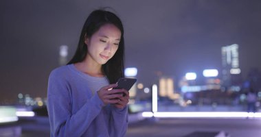 Asyalı kadın cep telefonuyla şehirde geceleri 
